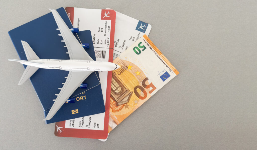 Miniatuur vliegtuig met paspoorten, instapkaarten en een biljet van 50 euro, symbool voor vliegtickets en reisannulering.