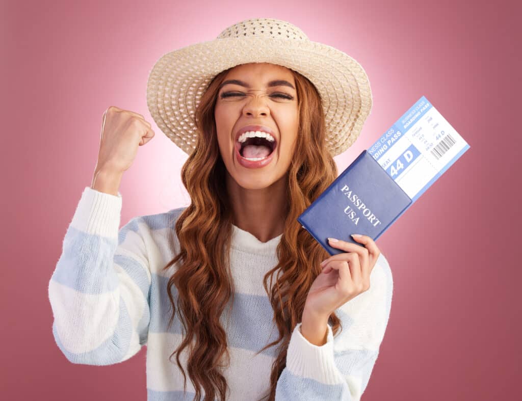 Vrolijke vrouw met een hoed die een Amerikaans paspoort en vliegticket vasthoudt, klaar om haar vlucht direct te boeken.