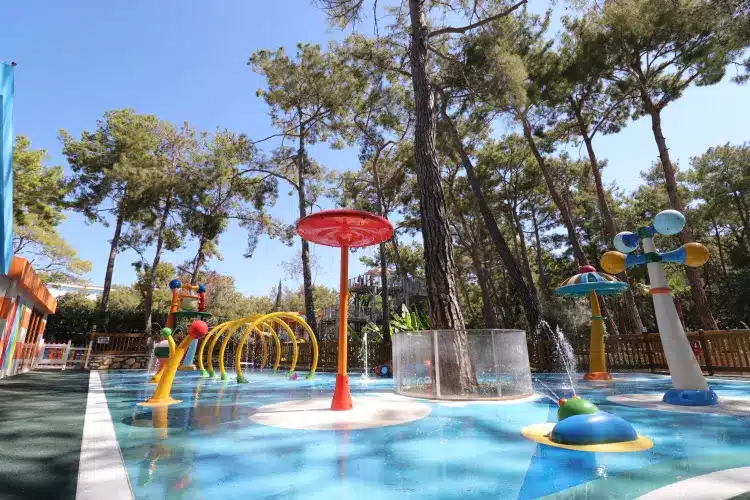 Kindvriendelijk waterspeelpark met kleurrijke fonteinen in bosrijke omgeving
