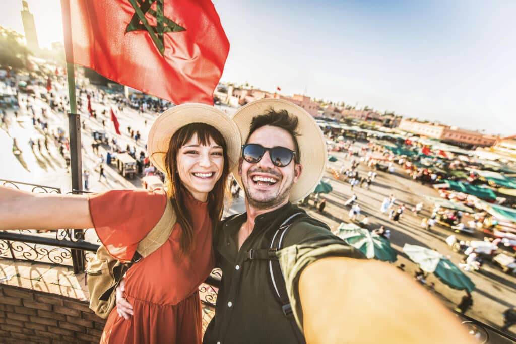 Twee toeristen genieten van hun vakantie in Marrakech met uitzicht op het levendige Jemaa el-Fna plein – vliegtickets bestemming Marokko