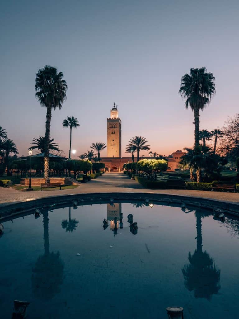 Koutoubia-moskee bij zonsopgang in Marrakech met palmreflectie in de fontein – vliegtickets bestemming Marokko