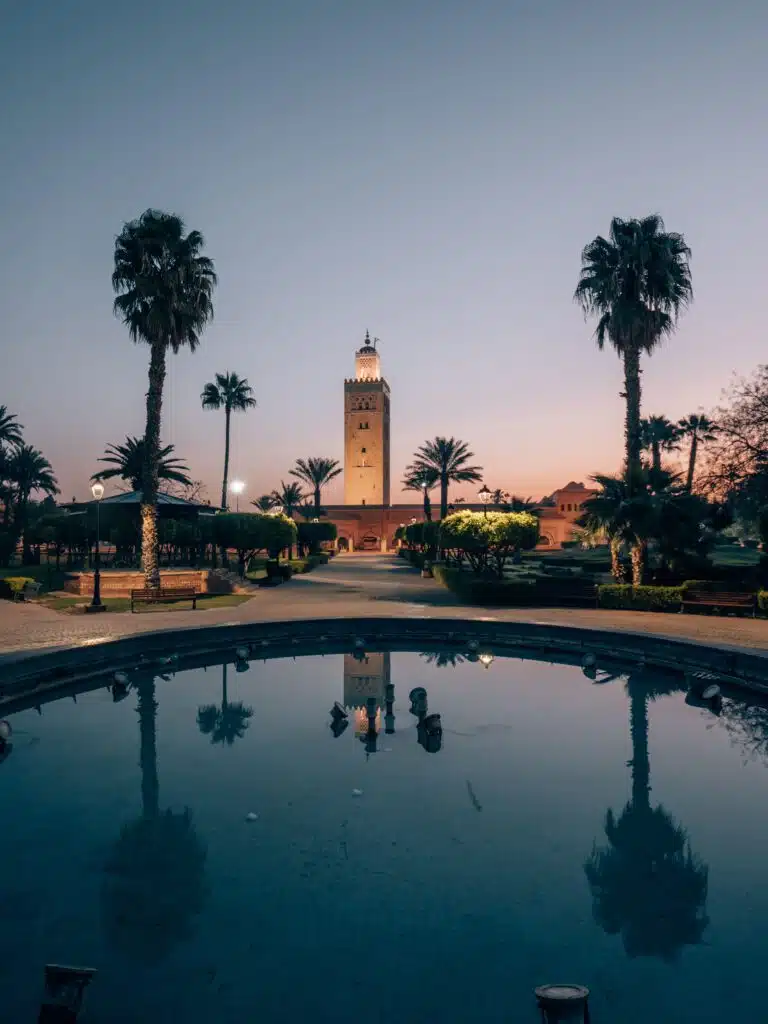 Koutoubia-moskee bij zonsopgang in Marrakech met palmreflectie in de fontein – vliegtickets bestemming Marokko
