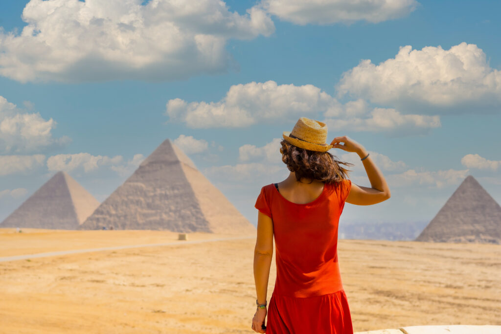 Vrouw bewondert de piramides van Gizeh in Egypte – vliegtickets bestemming Egypte