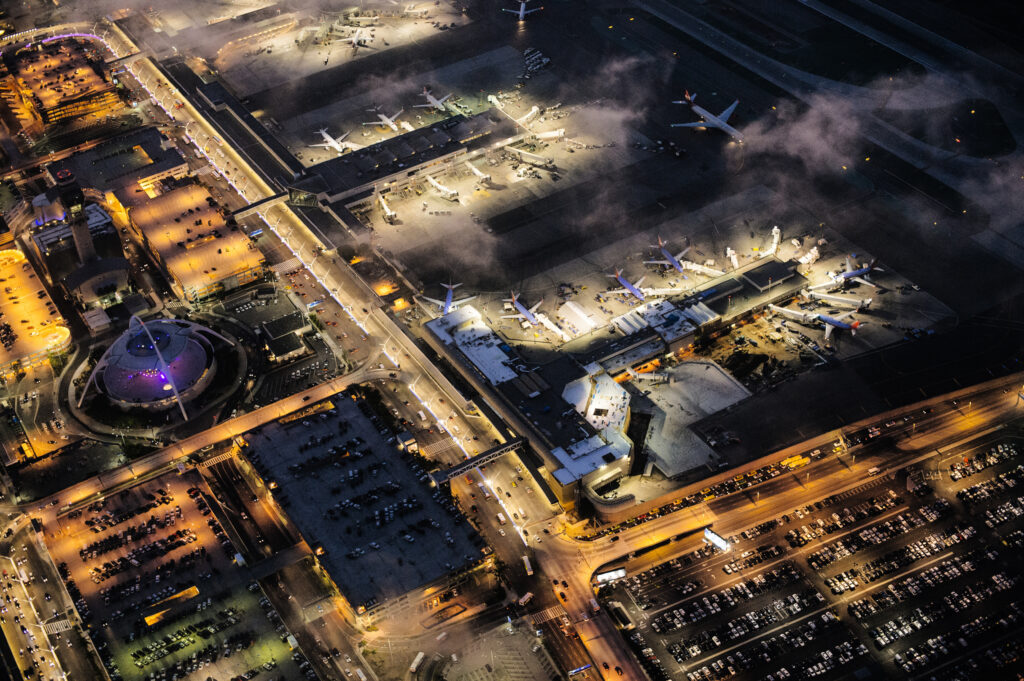 Luchtfoto van een internationale luchthaven bij nacht met vliegtuigen aan de gates – Newark vs JFK Business Class vergelijking via Vlucht-Ticket.nl