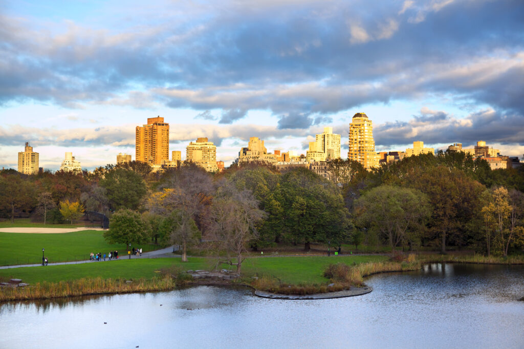 Bezoek Central Park in de herfst: bomen in warme kleuren met uitzicht op de skyline en vijver in New York