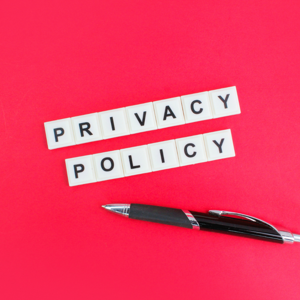 Witte letterblokken met de tekst ‘Privacy Policy’ en een pen op een rode achtergrond.