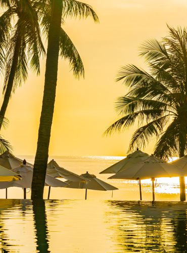 Zonsondergang met palmbomen en een strandresort in Azië, een serene bestemming voor moslimreizigers. Boek jouw verblijf via vlucht-ticket.nl / hotels