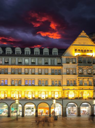 Verlichte gevel van een historisch gebouw in Europa tijdens een sfeervolle avond. Ontdek halal hotels via vlucht-ticket.nl / hotels.