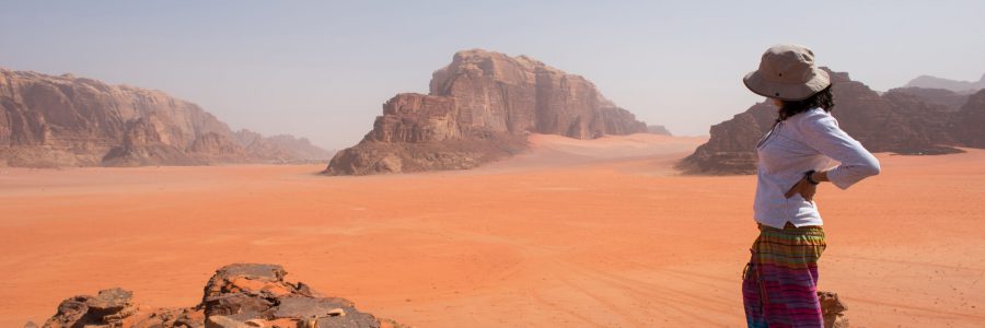 Reiziger geniet van het uitgestrekte uitzicht over de rode woestijnlandschappen van Wadi Rum in Jordanië.