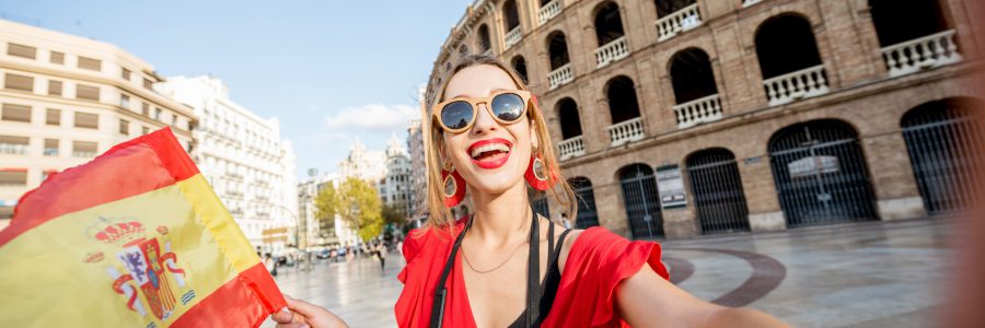 Vrolijke vrouw met een Spaanse vlag in Valencia, Spanje, symbolisch voor voordelige last minute vakanties."